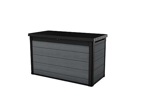 Coffre de jardin Keter Cortina gris à effet bois, ouvert près d’une terrasse dans un jardin ordonné.